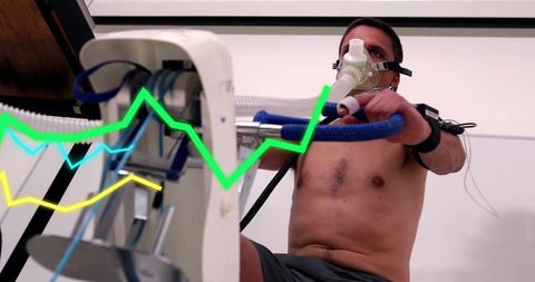Athlete in respirator training on gym bike with data visualization