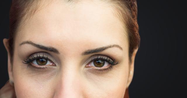 High-resolution close-up focusing on a woman's eyes against a dark background. Suitable for use in beauty and makeup advertisements, health and skincare promotions, or websites focusing on eye care products. The focus on the eyes can also imply themes of vision and focus for more abstract uses.
