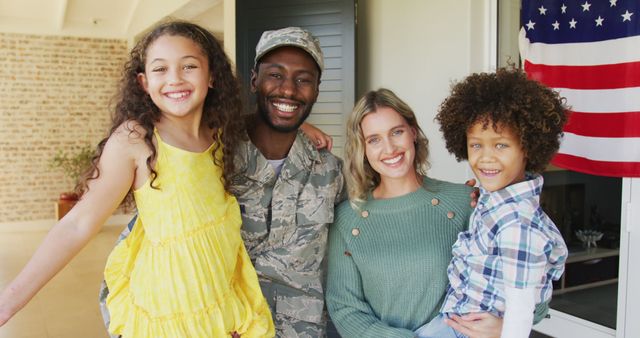 Image of happy diverse family standing outside of house. American patriotism, armed forces and family life.