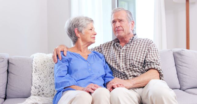 Cute elderly couple talking on sofa