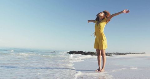 Confident young woman embracing freedom by the ocean