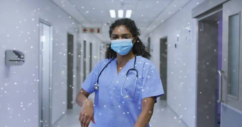 Female nurse walking hospital corridor in mask and scrubs with falling snow particles