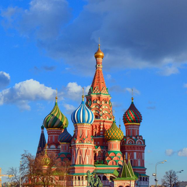 Photo features St. Basil's Cathedral with its iconic colorful onion domes under a clear, sunny sky. This can be used in travel blogs, tourism brochures, cultural heritage studies, and educational material about Russian architecture. Ideal for promoting tourism to Moscow and highlighting architectural marvels.