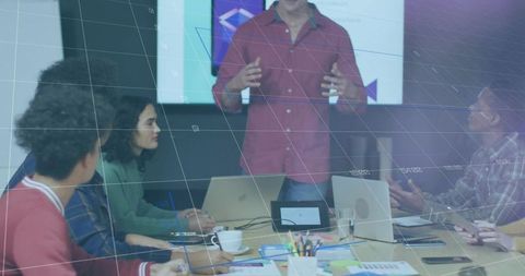 Male presenter leading team meeting in modern boardroom with laptops and charts