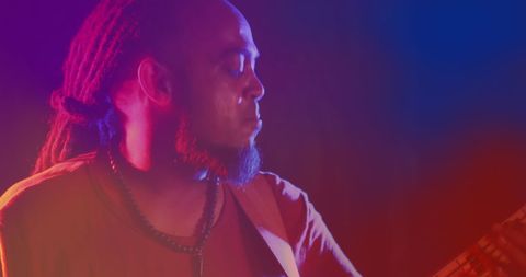 Musician with Dreadlocks Playing Bass Guitar in Vibrant Lighting - Download Free Stock Images Pikwizard.com