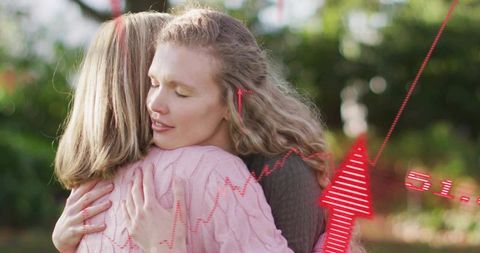 Women embracing in garden sharing comfort and support with warm natural light