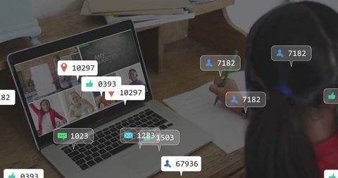 Girl writing while watching online class with social media engagement overlays on laptop