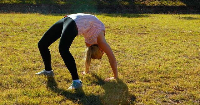 Woman Performing Stretching Exercise in Sunny Grassy Field - Download Free Stock Images Pikwizard.com