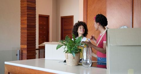 Lesbian Couple Happily Unpacking in New Home with Houseplants