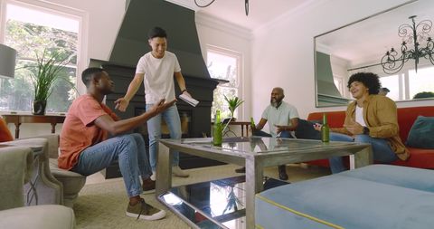 Diverse Group Laughing in Living Room With Drinks Enjoying Moment