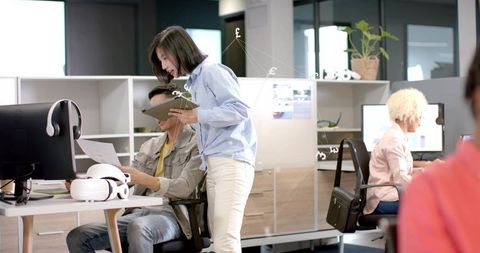 Colleagues collaborating over tablet in modern open-plan office with VR headset
