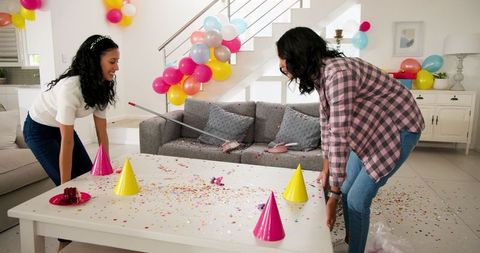 Women cleaning up after colorful birthday celebration in living room