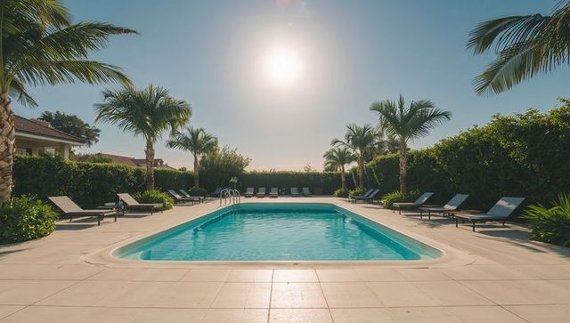 Sunlit resort pool with palm trees and loungers on tiled deck, symmetrical composition