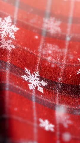 Swaying red plaid fabric with drifting white snowflakes vertical close-up loop