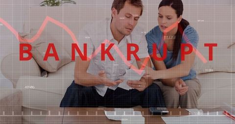 Stressed couple reviewing finances with bankruptcy graph overlay