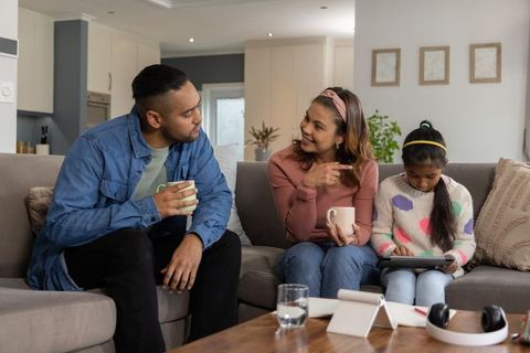 Cozy family moment on sectional sofa while child using tablet and parents chatting