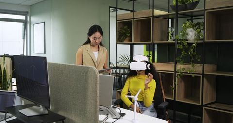 Coworkers Using VR Headset and Tablet in Innovative Green Office