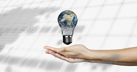 Levitating earth lightbulb presenting innovation and sustainability above human palm