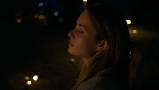 Young woman gazing on bench at night with candlelight glow and soft bokeh serene atmosphere