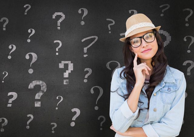 Woman in straw hat and glasses stands pensively in front of a black chalkboard with multiple question marks. This visual can be used for ideas and creativity related concepts, solving problems in education, decision-making scenarios, and exploring various strategies or solutions.