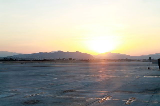 Sunrise casting a golden glow over an empty airport runway. Perfect for travel, aviation, serenity, or morning calmness concepts. Ideal for blogs, articles, or websites emphasizing peaceful beginnings, travel journeys, or aviation industry themes.