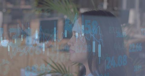 Businesswoman analyzing financial charts with blue data overlay in office workspace
