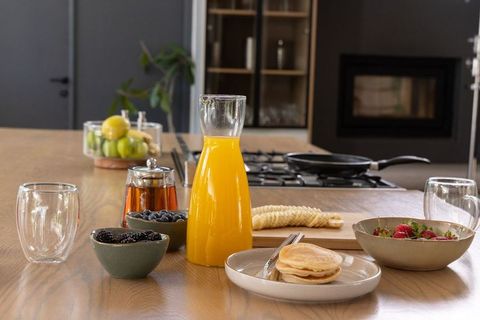 Serving rustic breakfast spread with orange juice carafe, pancakes and fresh berries