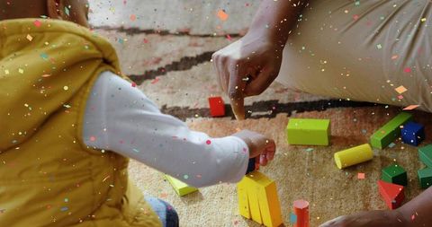 Toddler stacking colorful wooden blocks on rug with parent guiding playful early learning