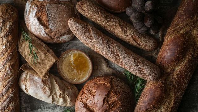 Rustic artisan breads and seeded baguettes with honey jar, grapes and rosemary