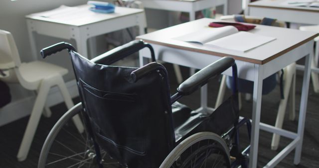 Image of empty wheelchair standing at desk in classroom. disability, primary school education and learning.