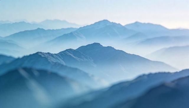 Ethereal blue mist mountains panorama featuring sunlit central ridge, layered fog and haze