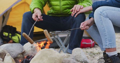 Couple Roasting Sausages by Campfire in Cozy Outdoor Setting