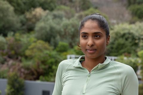 Adult asian woman standing on terrace wearing light green zip-up athletic top outdoor portrait