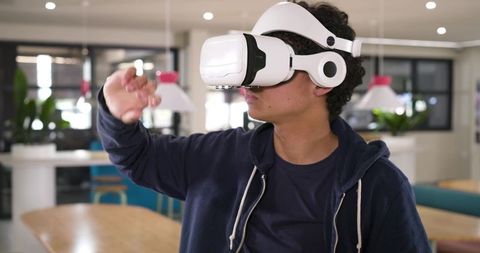 African american male using white vr headset interacting with virtual workspace in coworking
