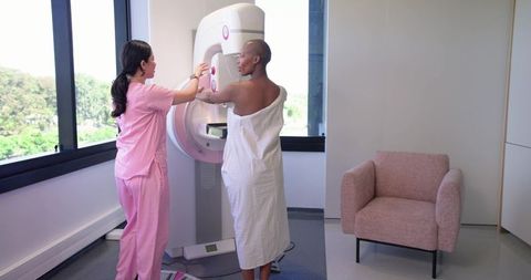Technologist positioning african american patient for mammography screening in clinic