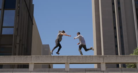 Two Men Practicing Parkour on City Building in Sunny Weather