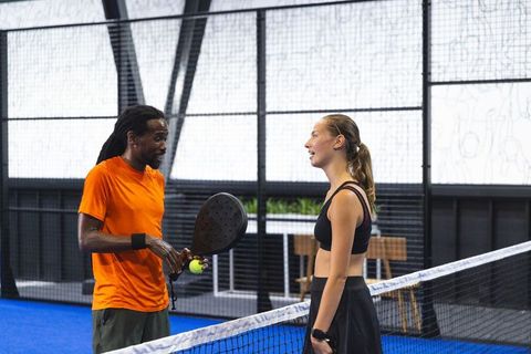 Diverse athletes conversing on blue padel tennis court for recreational match