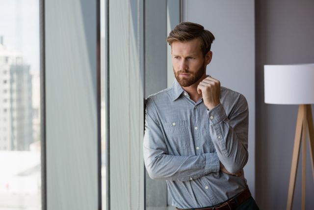 Thoughtful male executive looking through window in office