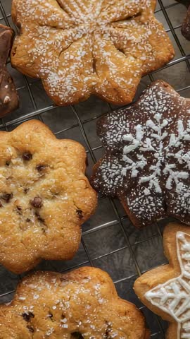 Vertical video panning across star and snowflake iced cookies on wire rack