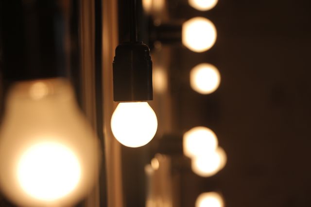 Close-up view of illuminated light bulbs lined up, emitting warm glow. Ideal for concepts related to technology, energy efficiency, lighting solutions, and indoor atmospheres.
