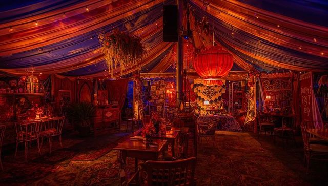 Glowing bohemian lounge tent with oversized red lantern, tapestry, cozy rugs and ambient lighting