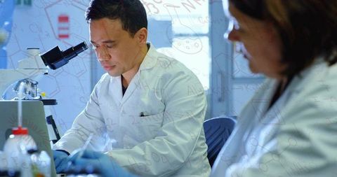 Scientist preparing samples for microscopy in collaborative wet lab with pipette and microscope
