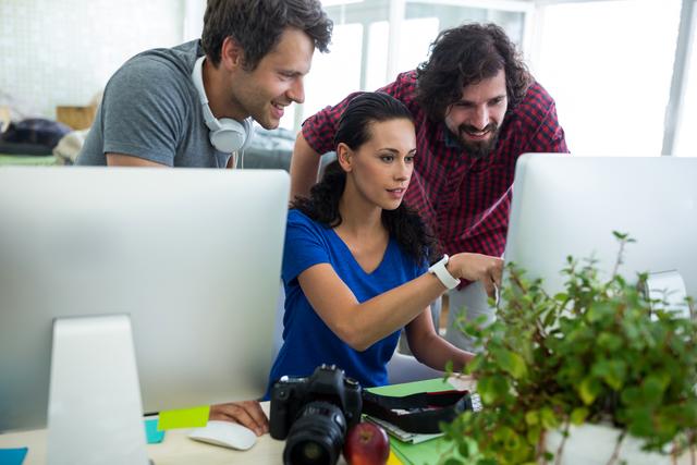 Group of graphic designers interacting over computer in office