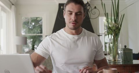 Man Focusing on Work at Home Office with Laptop and Coffee