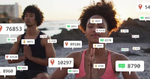 Couple meditating on rocky shore at sunset with social media notification overlays