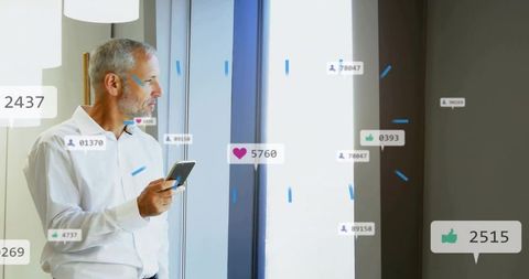 Senior professional holding smartphone looking out office window with social media overlay