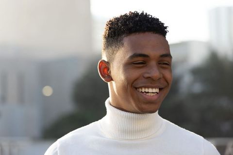 African American Man Smiling on Rooftop Wearing White Turtleneck During Golden Hour