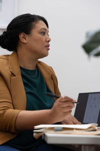 African american professional woman presenting ideas with laptop and notebook in office