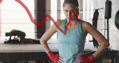 Determined female boxer wearing teal top and red hand wraps with performance chart overlay