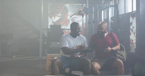 Two african men shaking hands after workout in urban gym with colorful graffiti mural